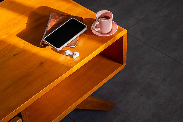 Wooden table with smartphone, notebook, wireless earbuds and cup of coffee. Cozy home office setup.