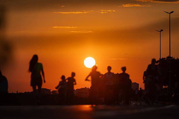 istock People silhouettes on pedestrian walkway at sunset. 2242107133