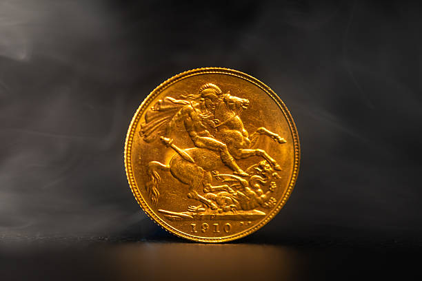 A close up of a 1910 gold sovereign on a dark smoky background.