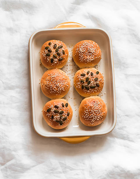 istock Buns with pumpkin and sesame seeds in a baking dish on a light background, top view 2242110709