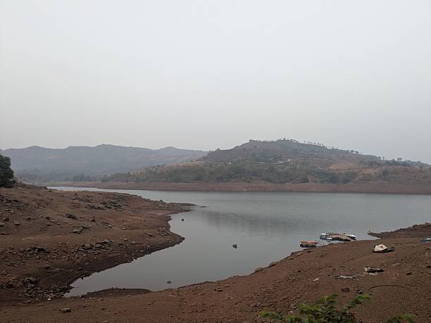 istock Misty morning lake view with distant green hills 2242111527