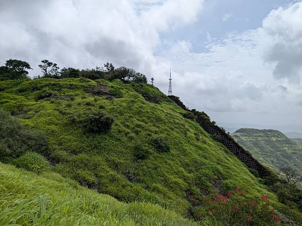 istock Lush green hillside with communication towers under dramatic cloudy sky 2242111546