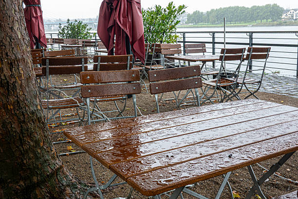 istock Empty outdoor beer garden tables on a rainy day by a river 2242115132