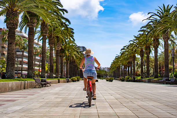 Mature woman riding bicycle at seaside boulevard