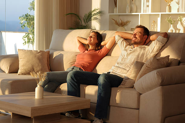 istock Happy couple relaxing sitting on a sofa at sunset at home 2242125362