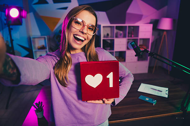 istock Content creator holding heart-shaped prop symbolizing engagement in styled office with trendy decoration and neon lights 2242127191