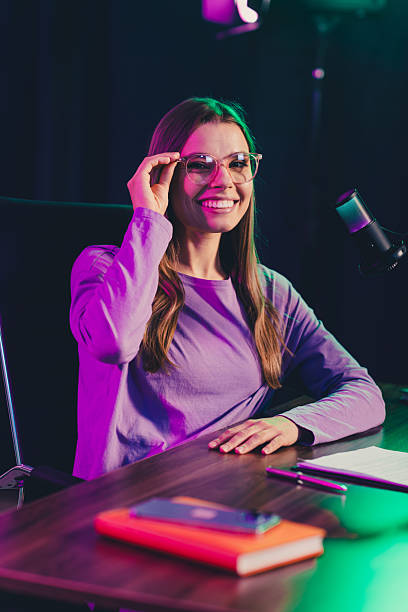 istock Confident Young Woman Blogger with Microphone Working in Neon-Lit Office Exploring Media Industry in Evening Indoors 2242127207