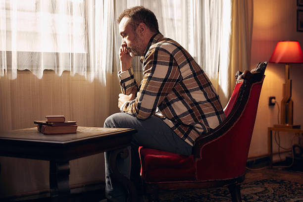 Man with depression sitting on a chair at home.