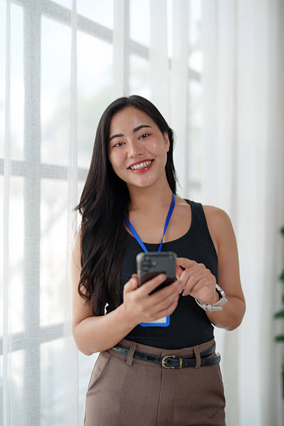 istock Young asian businesswoman using smartphone and smiling at camera 2242133144