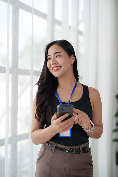 istock Young businesswoman using smartphone and smiling near window 2242133146