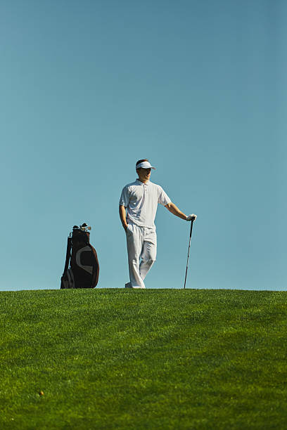 istock Golfer standing with club and bag on sunny course 2242136532