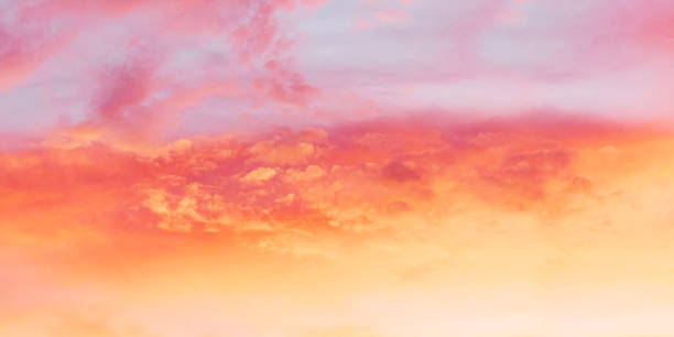 istock Vibrant sunset or sunrise sky dominated by intense saturated colors ranging from soft pale blue at the top to a glowing yellow-orange at bottom with dramatic layers of pink and fiery coral-red clouds 2242137994