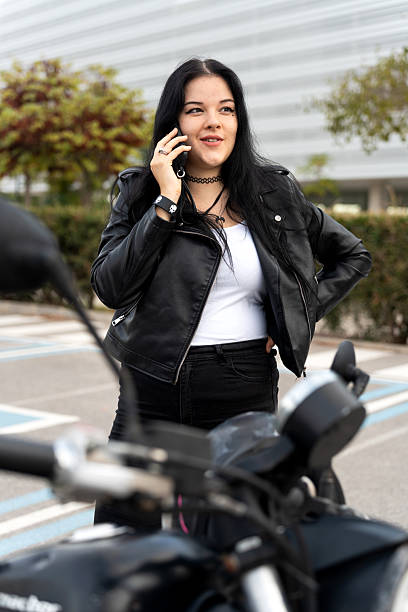 istock Biker woman talking on phone next to motorcycle 2242141037