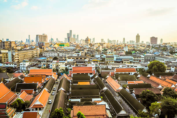 An aerial view of Bangkok, Thailand, showcasing the unique contrast between traditional temple roofs and a modern city skyline.