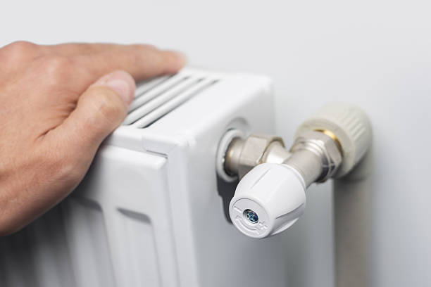istock Man warms up hands over heater. Concept of the need for good central heating 2242143133