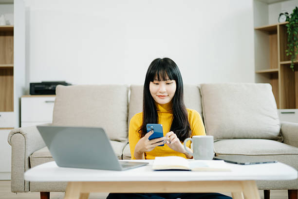 istock Young woman relaxing on couch using smartphone and smiling while browsing onlineuse cellphone 2242144252