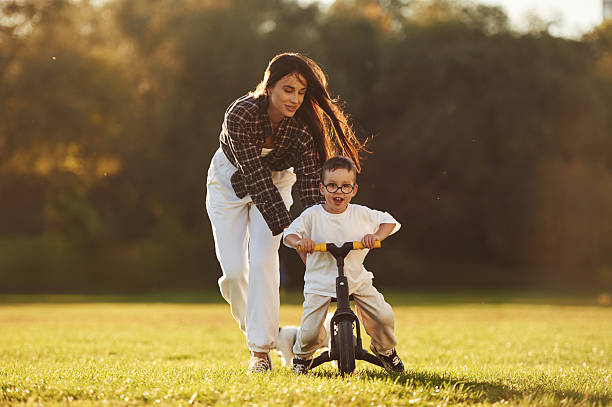 istock Learning to ride a bicycle. Mother and son together in an open field during daytime 2242145232