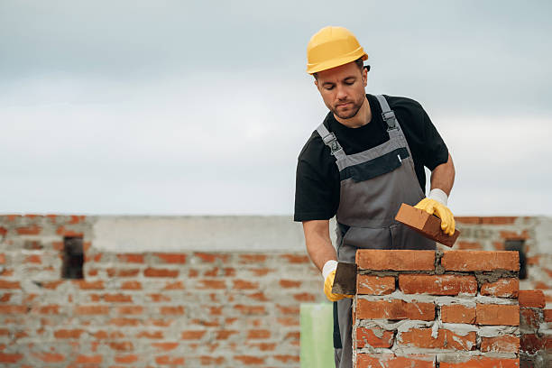 istock Placing the bricks, making a wall. A builder is working at the construction site at daytime 2242148288
