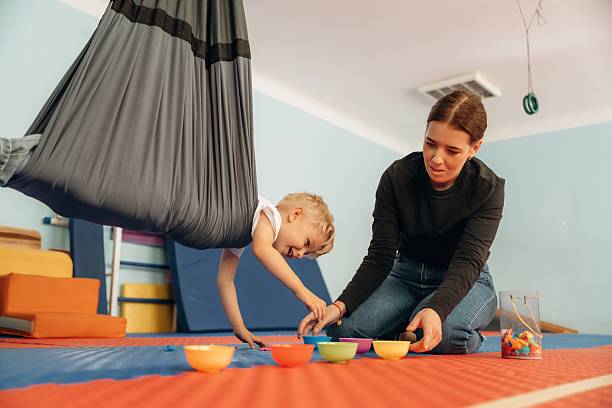 istock Putting the objects into bowls while hanging. Preschool child with teacher during developmental activities in a playroom 2242149656