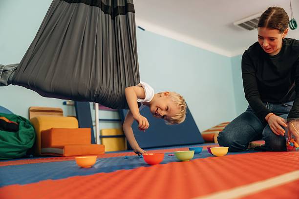 istock Putting the objects into bowls while hanging. Preschool child with teacher during developmental activities in a playroom 2242149671