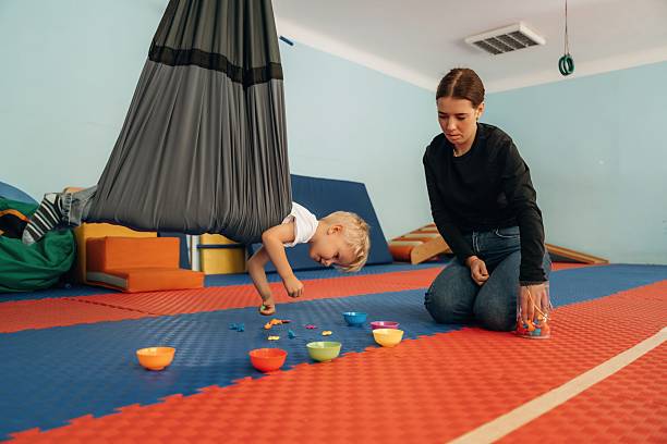 istock Putting the objects into bowls while hanging. Preschool child with teacher during developmental activities in a playroom 2242149683