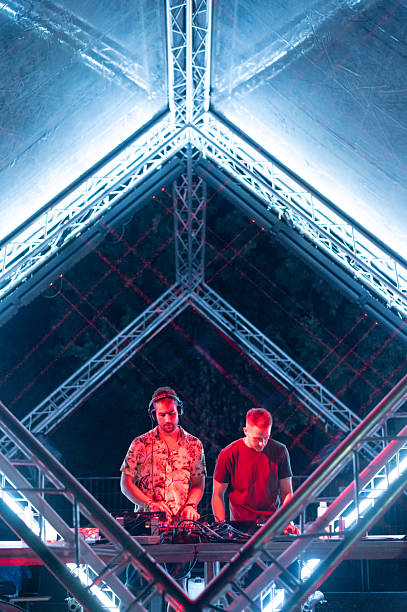 Two club dj's playing techno music on the modern stage at the summer night concert.