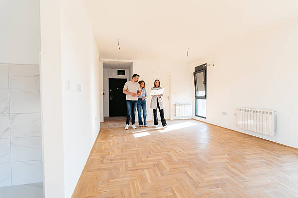 istock Female Architect Looking At The Design Blueprint While Walking With A Young Couple In Their Apartment 2242162302