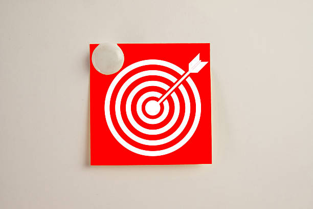 Business goal and success concept. Arrow hitting the center of a target or bullseye on a red note pinned to a board. Symbol of achieving objectives, mission accomplishment, and successful focus.