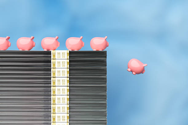 Piggy banks standing on a large stack of banknotes with one falling down, representing financial crisis, savings, investment and economy