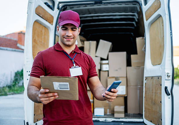 istock Delivery man scanning package with smartphone from van 2242166311