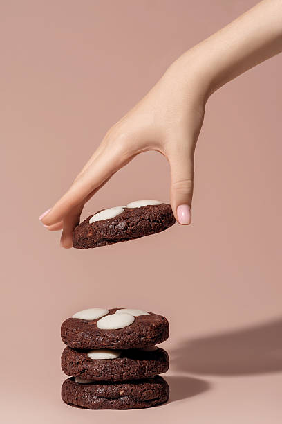 istock Hand reaching for chocolate cookies with white chocolate chips on a soft pastel background with copy space 2242166326