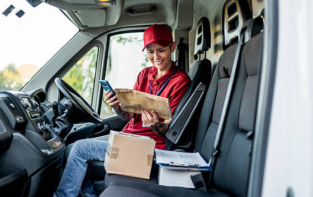 istock Woman courier checking deliveries on mobile phone inside van 2242167275