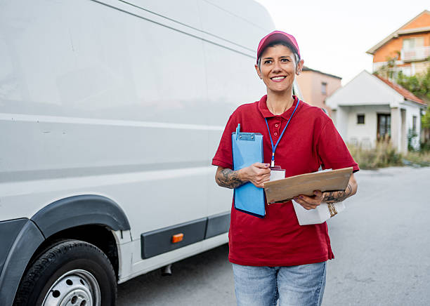 istock Woman courier delivering package standing by delivery van 2242167476