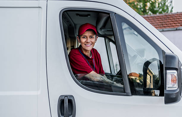 istock Woman courier driving delivery van smiling 2242167493