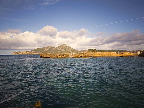 View of Sant Elm and Dragonera Island on the west coast of Mallorca, bathed in soft Mediterranean light. The turquoise sea, rocky textures, and sea caves create a tranquil yet powerful landscape. A portrait of natural balance between sea and stone in the Balearic Islands.