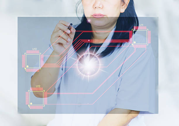 istock Image of a young woman using an electronic pen to touch a transparent display screen, with graphics of electronic circuits and computer chips. 2242169826