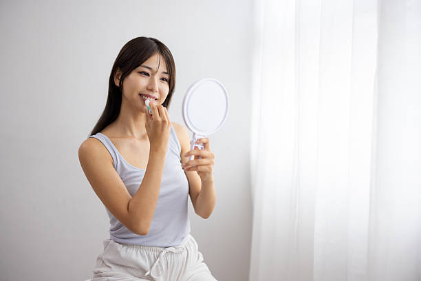 istock Young Woman Applying Lip Balm While Holding a Hand Mirror 2242171005