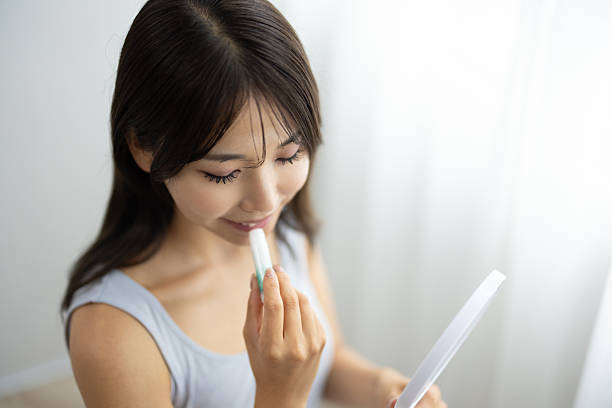 istock Young Woman Applying Lip Balm While Holding a Hand Mirror 2242171051