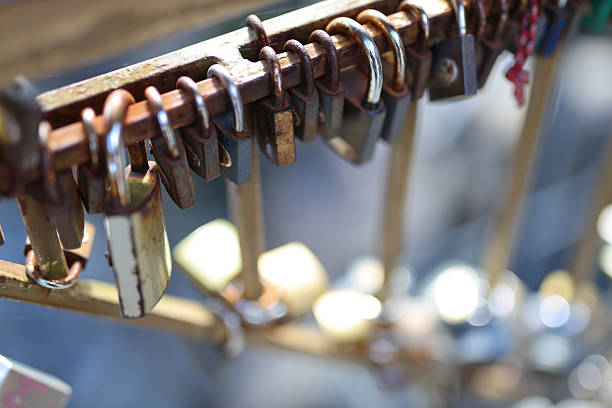 Rusty love locks attached to metal railings on sunny day.