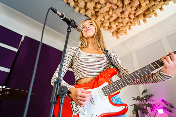 Attractive model, Girl, woman dreams with guitar in studio.
