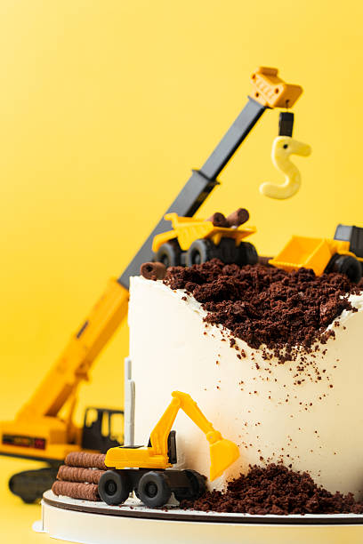 istock Birthday cake for five year old kid, decorated with construction vehicles. Heavy car themed homemade cake for toddler boy birthday celebration with toy excavators and crane on the yellow background. 2242174815
