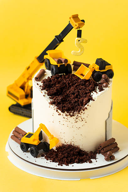 istock Birthday cake for five year old kid, decorated with construction vehicles. Heavy car themed homemade cake for toddler boy birthday celebration with toy excavators and crane on the yellow background. 2242174818