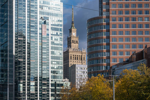 The Palace of Culture and Science framed between contemporary office buildings in Warsaw, Poland, showcasing the city’s dynamic blend of historic and modern architecture under soft autumn light.