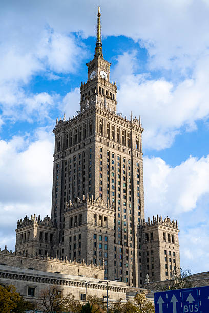 Detailed view of the Palace of Culture and Science in Warsaw, Poland, showcasing its historic design and clock tower against a vivid sky.