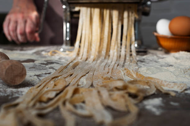 istock Caucasian female hands making fettuccine noodles using mechanical pasta machine 2242178842