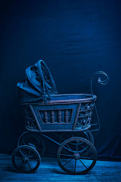 A creepy Victorian baby doll stroller on a black background with room for copy.