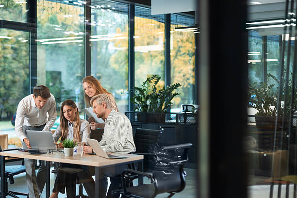 istock A modern office interior, featuring a blurred view of workers at desks, through a glass partition. 2242180405