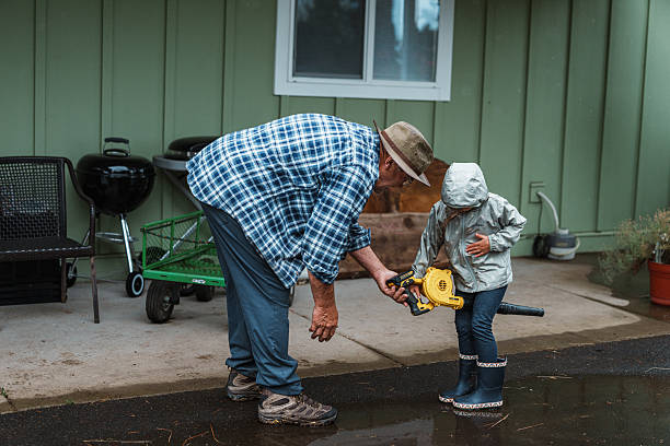 istock Grandfather teaching granddaughter how a leaf blower operates 2242185873