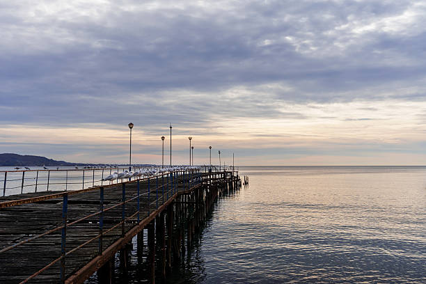 istock Wooden pier extending over calm waters under a cloudy sky at sunset with serene atmosphere 2242191199