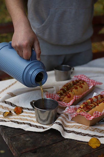 istock A person's hand pours a drink from a thermos into tin mugs 2242193980
